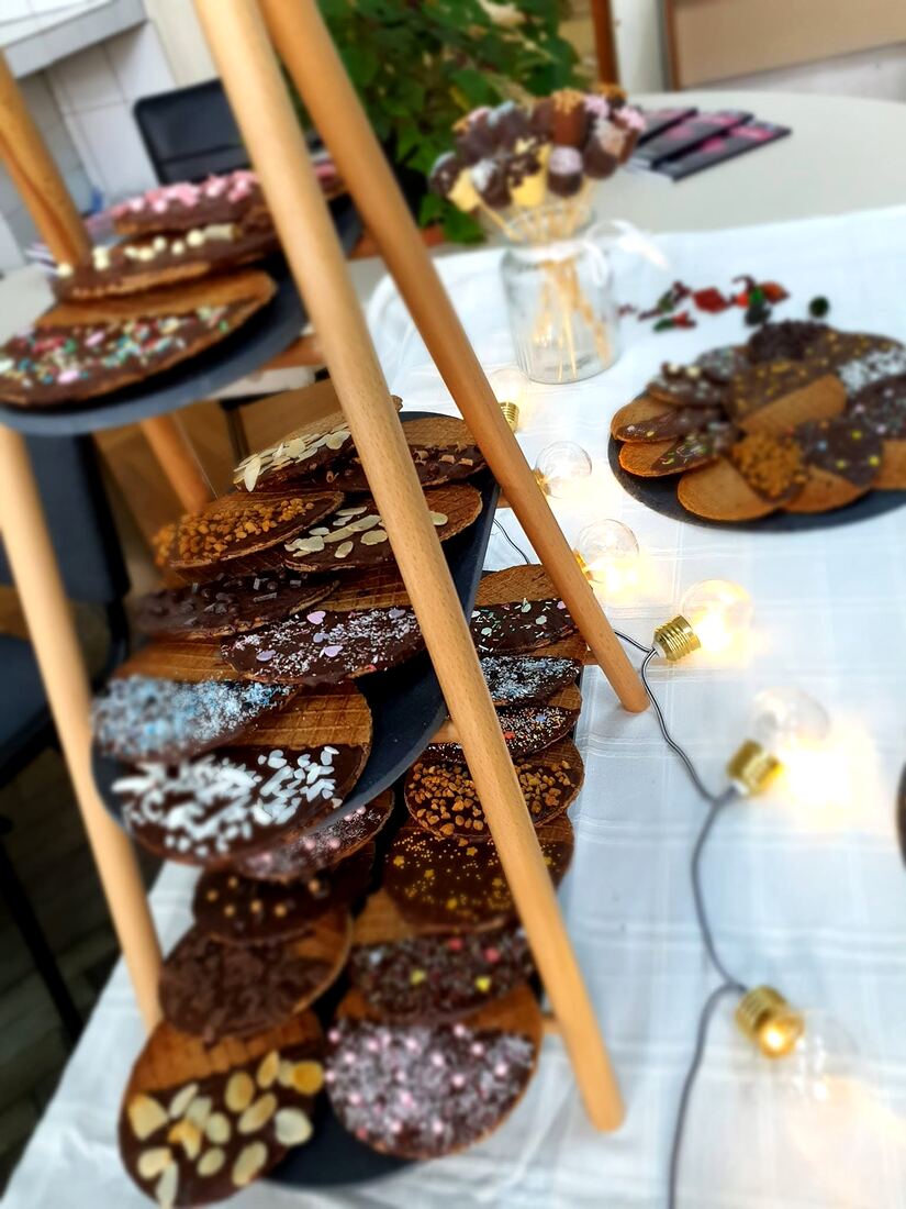 Etajere cu stroopwafels decorate și prăjituri, luminate cu ghirlande