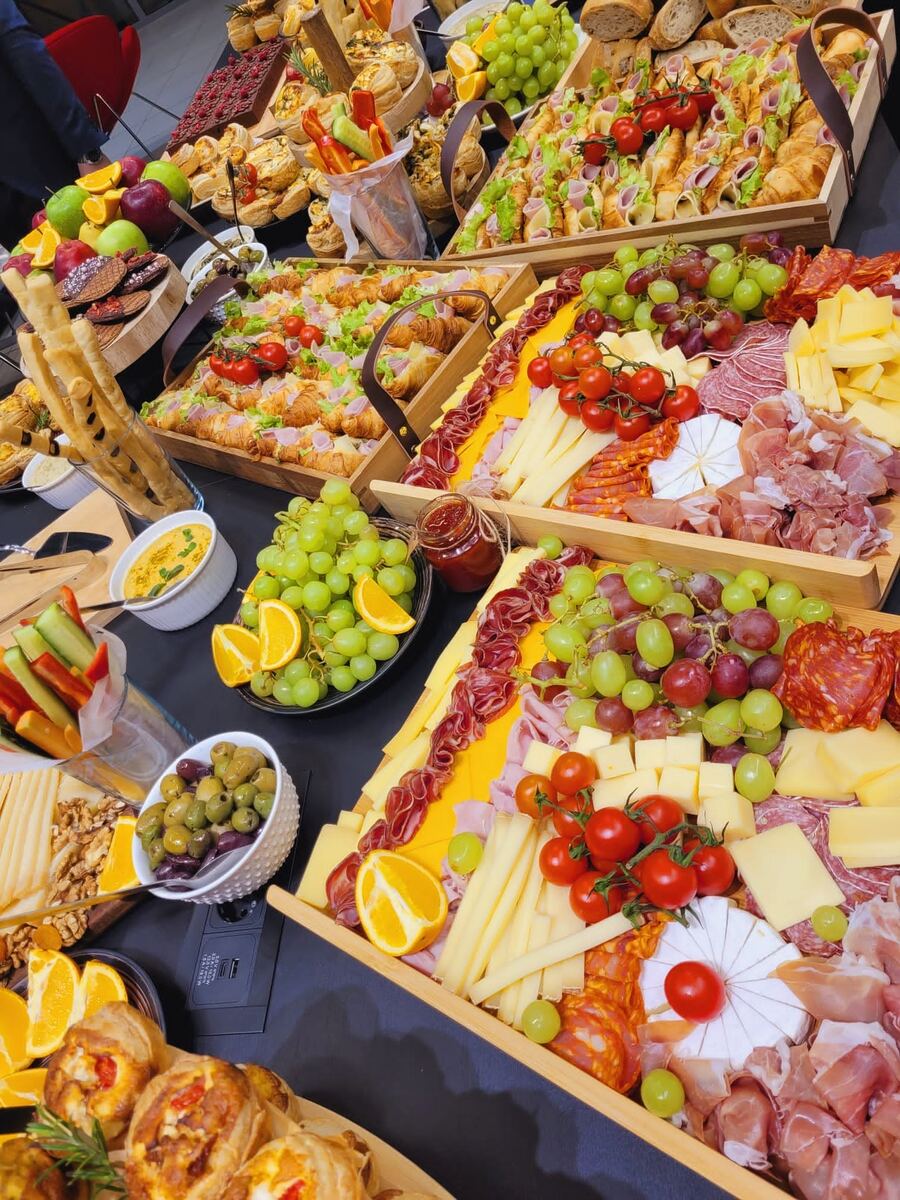 Platouri cu brânzeturi, mezeluri, fructe și grisine, așezate pe o masă de eveniment