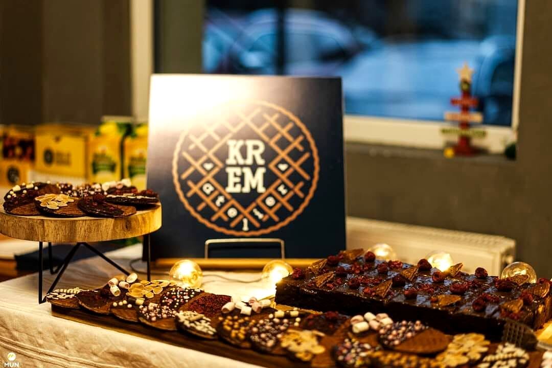 Placa cu sigla Krem Atelier așezată pe masa de eveniment, între platouri